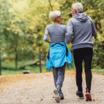 Older adult couple walks in a park.