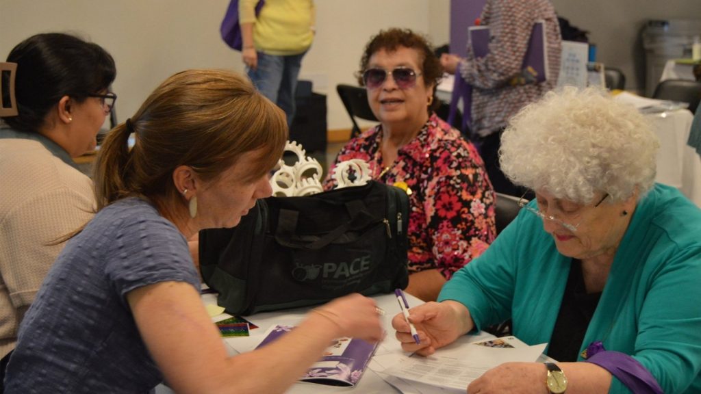 Three people gather around a table to learn about nutrition at the Brain Health and Community Resource Fair.