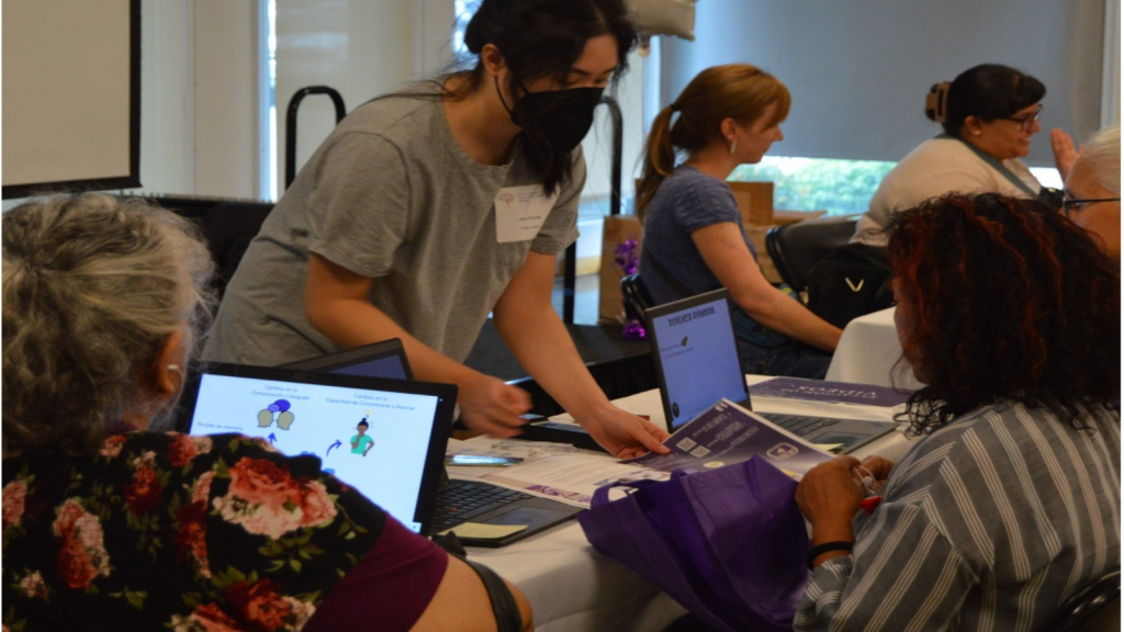 Three people gather around a table for video learning at the Brain Health and Community Resource Fair.