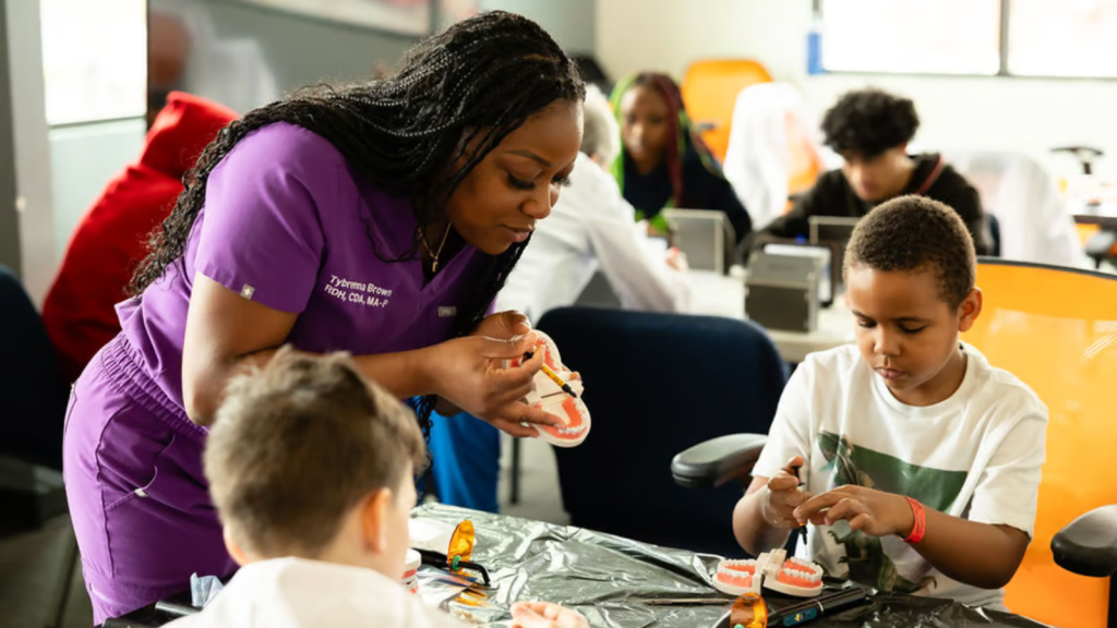 Dental professional points out different teeth on model to children in Delta Dental's Dental Career Discovery program.