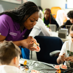 Dental professional points to teeth on model to teach youth in the Dental Discovery program.
