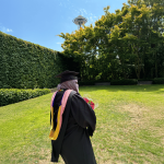 Samira Farah stands in front of the Space Needle in her academic regalia.