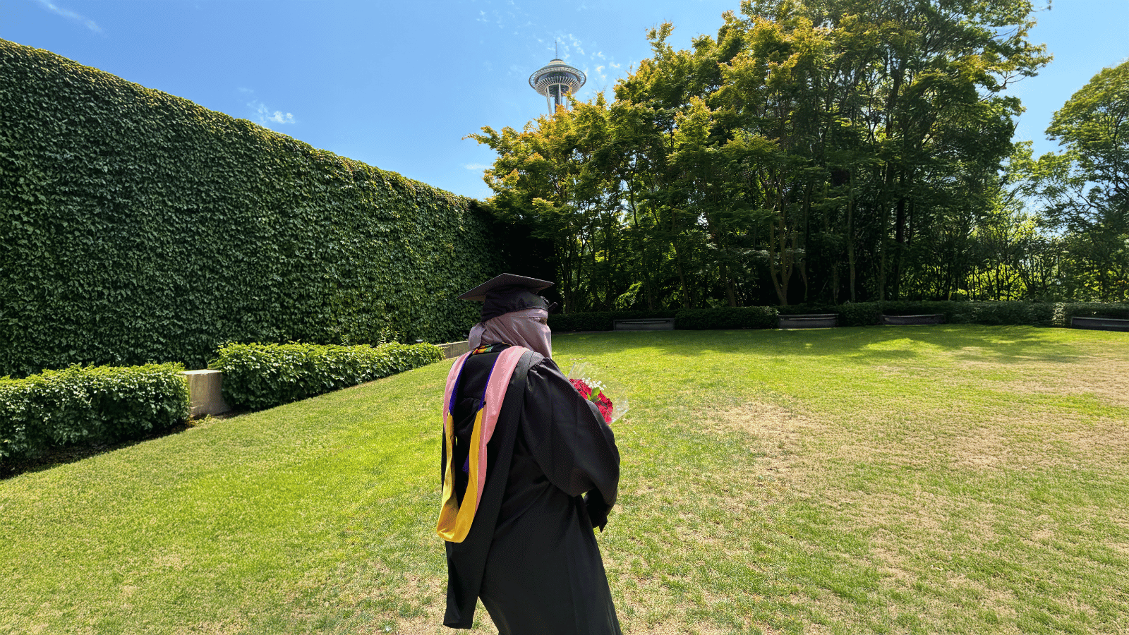 Samira Farah stands in front of the Space Needle in her academic regalia.